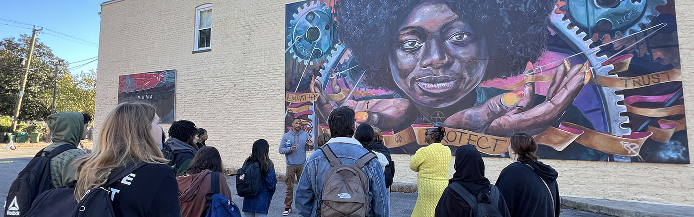 Students stand in front of a colorful mural in downtown Richmond