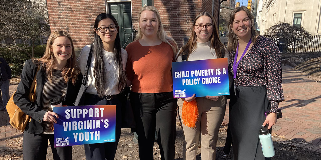 Five people stand, two holding signs that read: Support Virginia's Youth and Child Poverty is a Policy Choice.
