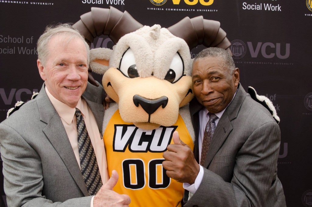 Two people stand next to the Rodney the Ram mascot